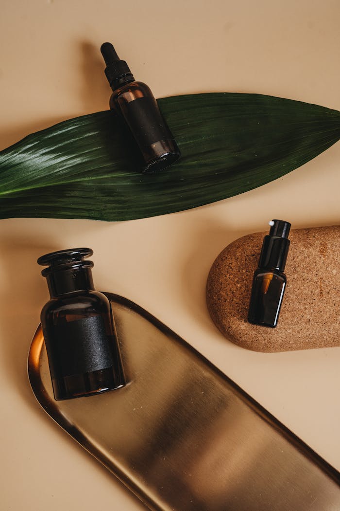 Stylish arrangement of cosmetic bottles with leaf and cork on beige backdrop, perfect for beauty branding.